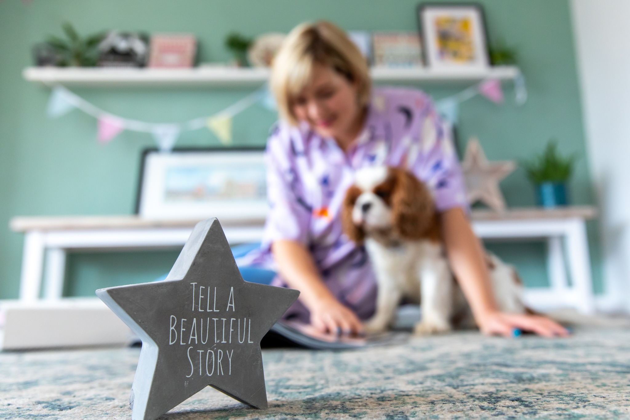 A picture of the owner of Brand Remarkable, Charlotte, sat with her dog. In the foreground is a star with the words "tell a beautiful story" on it