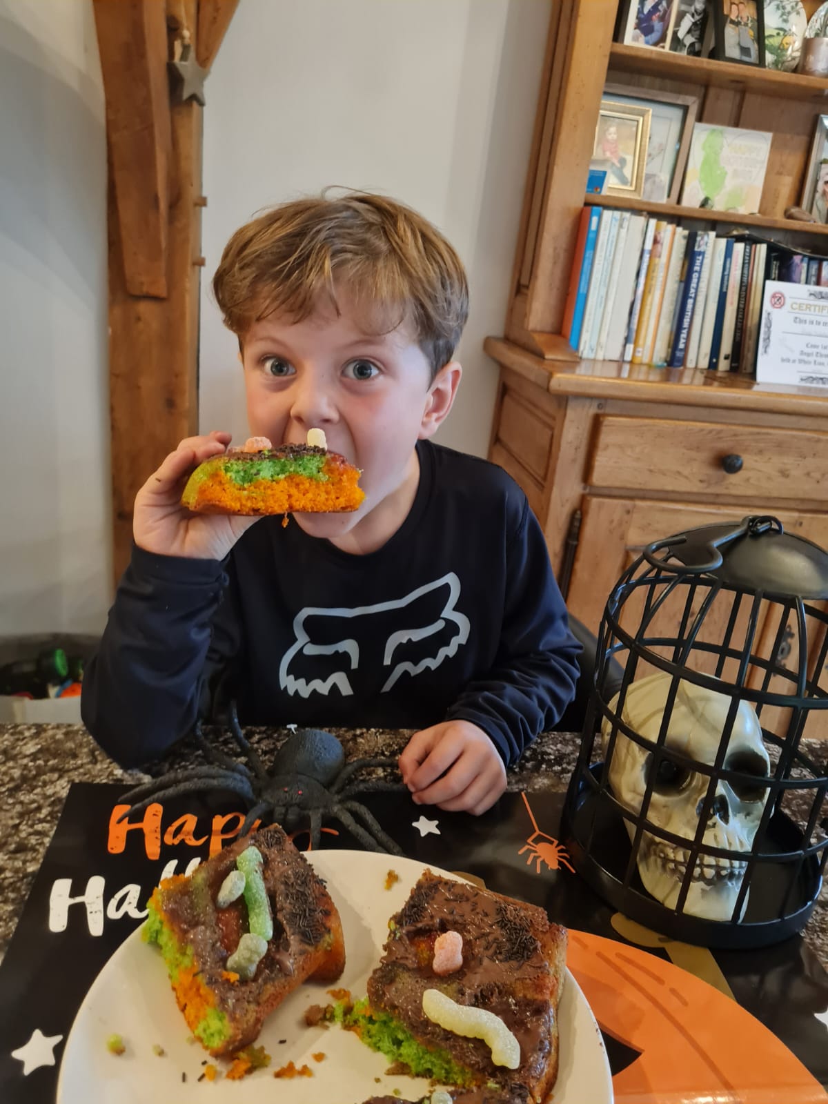 A little boy biting into a Halloween tray bake!